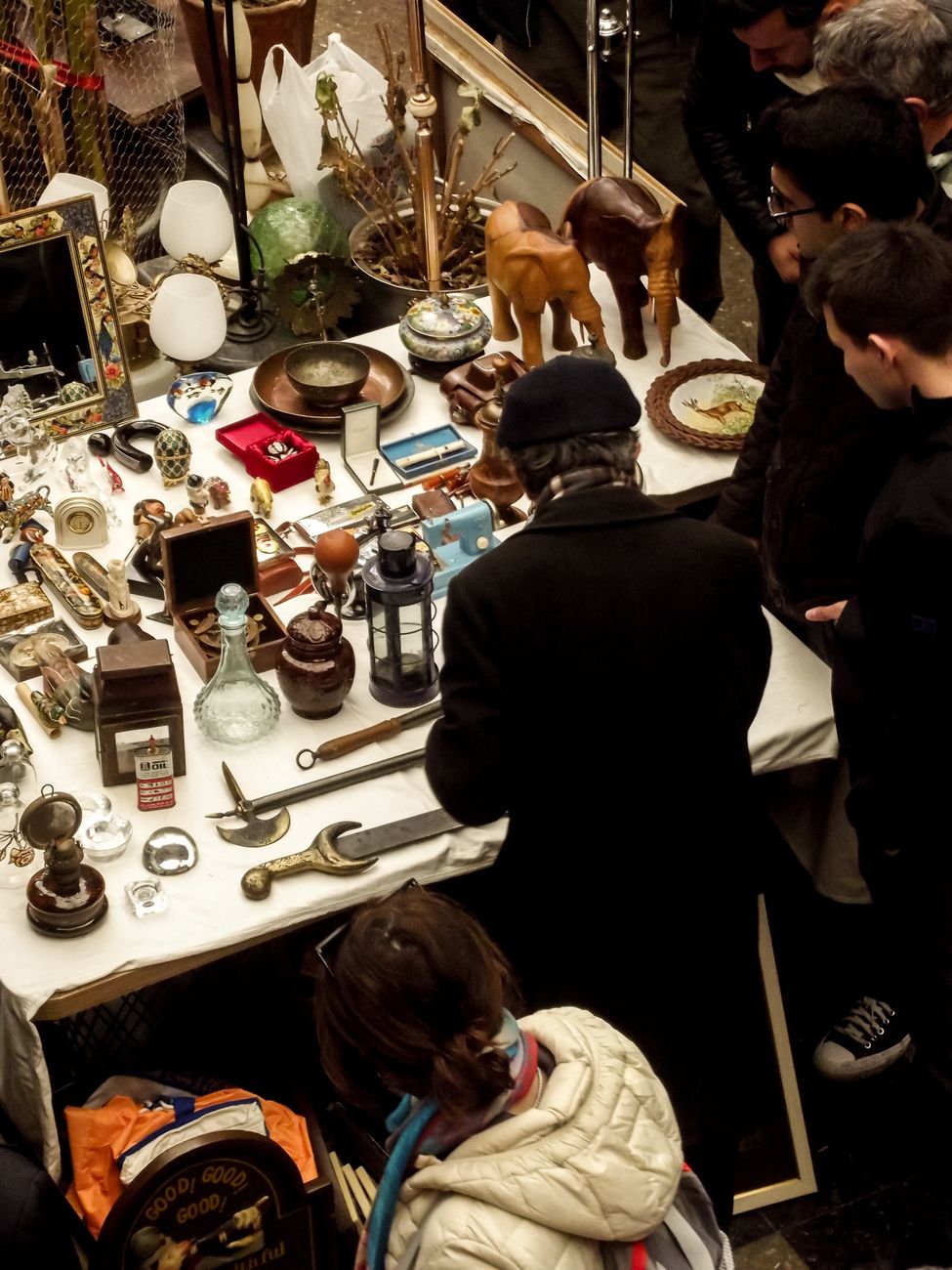 Shoppers browsing collectibles at an antique market stall